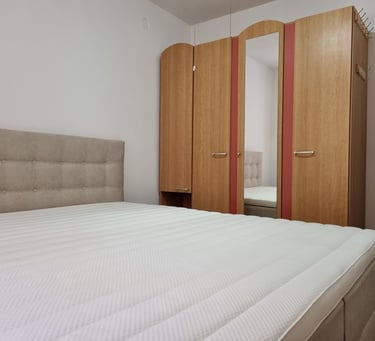 The photo shows a double bed with a mattress topper and wardrobes in the apartment's bedroom.
