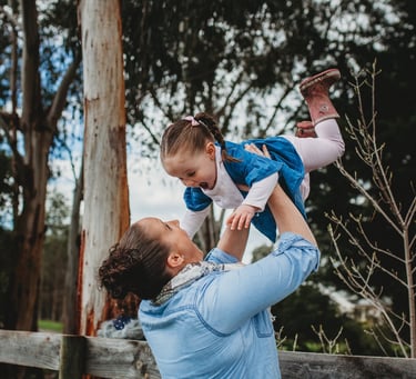 a woman holding a child over her head looking delighted