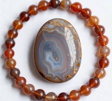 Polished agate bead bracelet encircling a raw septarian nodule gemstone on a black surface.