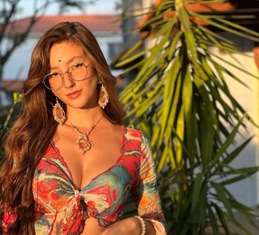 Mujer joven luciendo joyería de estilo bohemio y una blusa floral colorida, de pie al aire libre