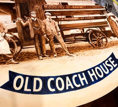 Close-up of angled pub sign with painted brewery staff