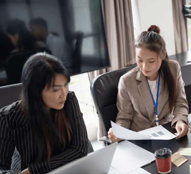 two women sitting at a table with papers and papers