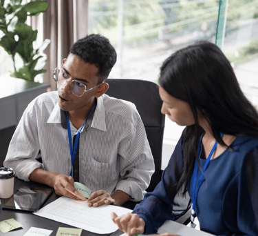 a man and woman sitting at a table with sticky notes