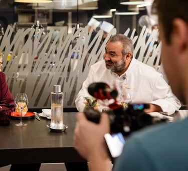 a man and woman sitting at a table with a camera