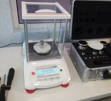 balanza analitica en calibración con juego de pesas al lado