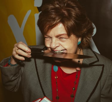 Mujer mayor divertida mordiendo un cuchillo y riendo para la marca de cuchillos Zwilling