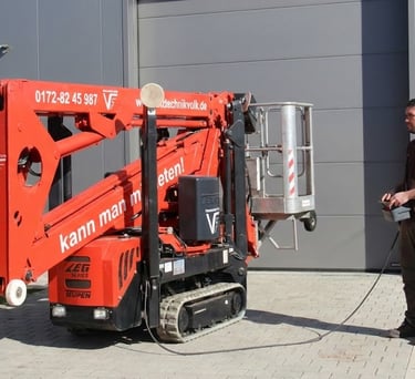 Schreinermeister Ferdinand Volk steuert die rote Raupen-Arbeitsbühne per Kabelfernbedienung vor seiner Werkhalle am Ammersee.