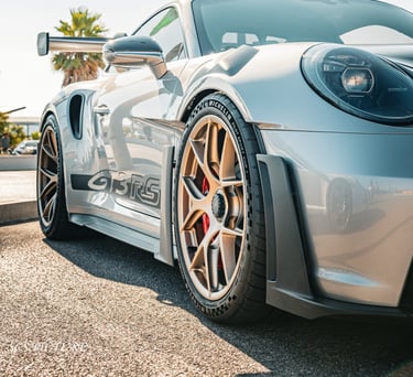 a silver sports car parked in front of a palm tree