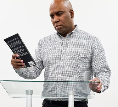 Lee A Jones standing at a podium with a book