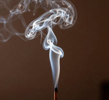 Photography of soft incense smoke curling in the air in a dark room, backlit by a saffron light. Mystical and serene atmosphere in a South Asian setting.