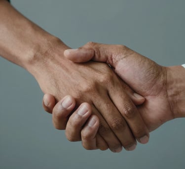 A close-up of two South Asian / Indian hands joined together in a supportive gesture, soft lighting, professional and compassionate atmosphere, warm tan and gray-blue tones in the background.