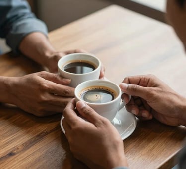 A close-up shot of two South Asian hands holding a warm cup of coffee during a conversation on a wooden table, emphasizing connection and support, soft morning light.