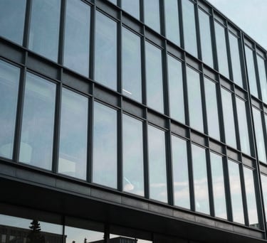An architectural photograph of a modern Danish office building with large glass facades, reflecting a pale sky blue, symbolizing transparency and progress in a professional context.