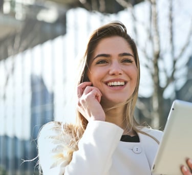 a woman talking on her cell phone and holding a tablet