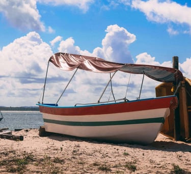 a boat on the beach with a sailboat in the water