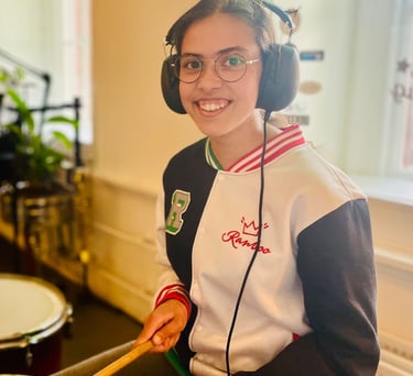a woman in a white jacket and headphones playing drums