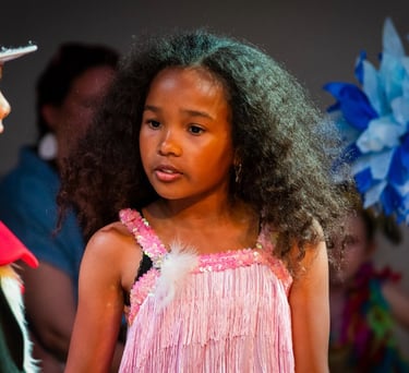 Two children performing in a production of Seussical Jr., with the girl in a pink fringe costume pla
