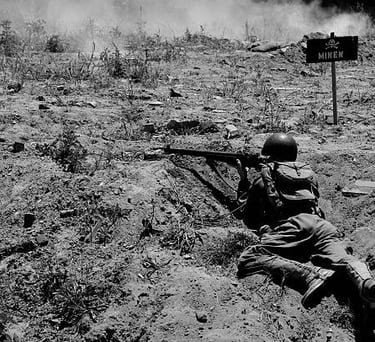 World War II soldier aiming a rifle from a trench near a German minefield warning sign.