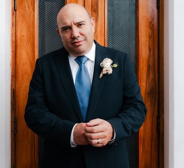 Novio en el día de su boda vestido con un traje elegante en una puerta de un salón de eventos en el centro histórico de Quito