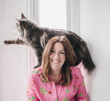 Photo of gabi, founder of the leopard mind loking at the camers smiling with her maine coon cat