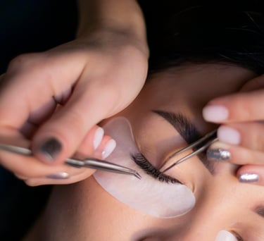 Lashista aplicando extensiones de pestañas técnica clásica en cabina profesional de belleza.