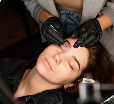 Profesional de cejas que da forma a las cejas con pinzas para una clienta en salón de bellleza