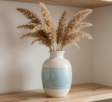 A close-up of a decorative ceramic vase with dried pampas grass on a light wooden shelf, soft natural lighting, Hispanic interior design style, colors of white and pale blue.