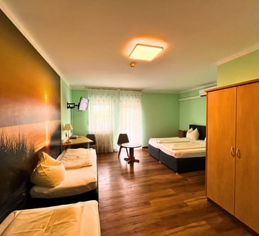 Modern hotel room featuring twin beds, wooden floors, and a scenic sunset wall mural.
