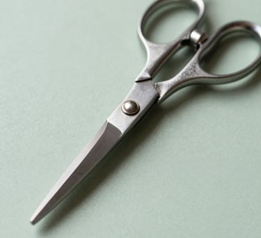 Macro photography of professional tailoring shears on a light green surface, emphasizing the sharp, clean lines and elegant metal design.