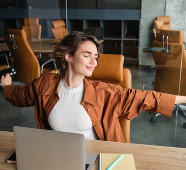 Mujer relajándose durante su jornada de home office, practicando una pausa de bienestar laboral 