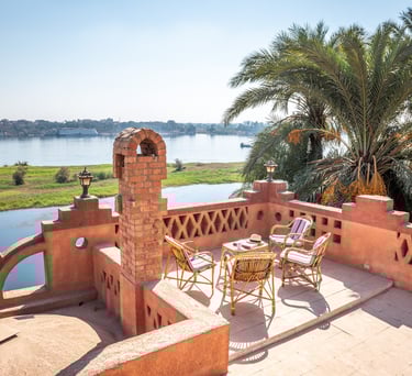 Terrace patio with wicker furniture overlooking the Nile River and palm trees in Egypt.