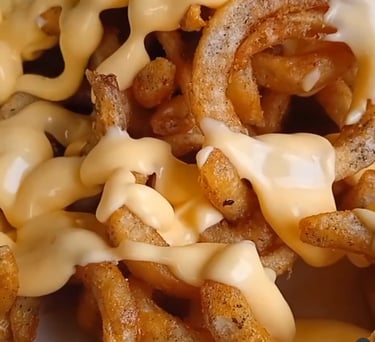 Patatas fritas rizadas, crujientes y sazonadas, bañadas en una cremosa salsa de queso fundido