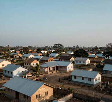 A wide-angle landscape shot of a South Asian rural village with clean, humble houses and a community center under a soft blue sky, symbolizing the foundation's reach.