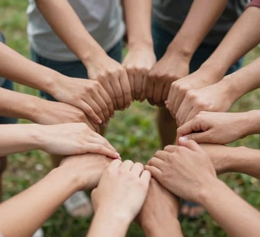 A close-up of a diverse group of hands joined in a circle, symbolizing collective wellbeing and unity, shot in a bright North American park setting.