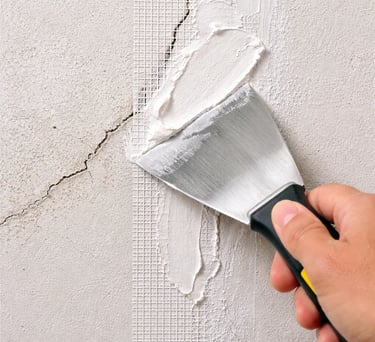 A man if fixing a crack on the wall