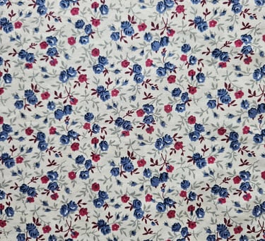 Vintage calico fabric with a ditsy floral print featuring small blue and pink roses on a white background.
