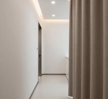 Detail of the dental clinic interior, white walls, soft textiles in taupe color, and a minimalist hallway with warm lighting.
