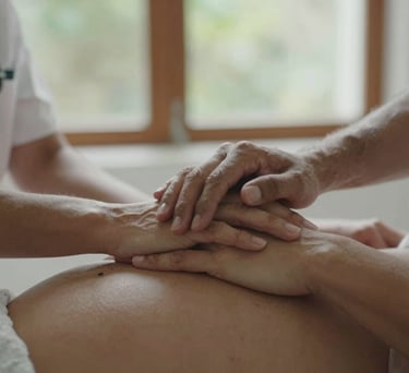 A close-up photograph of a professional South American therapist's hands gently holding a pregnant woman's hands, soft natural light through a window, conveying trust and connection.