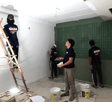 Professional house painters from Ghar Painting applying white and green paint to interior walls.