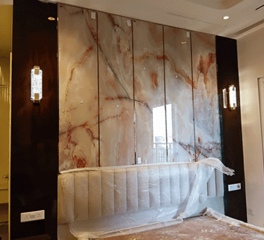 Luxury master bedroom featuring a polished onyx marble wall panel with modern gold sconces.
