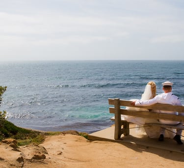 couple sitting on bench overlooking blue ocean at cuvier park