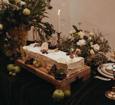 A sheet style wedding cake with white icing, surrounded by fruit and white and green flowers