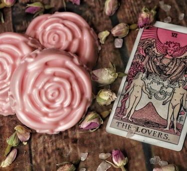 3 pink rose shaped soaps next to two tarot cards with a pink hue