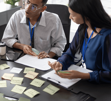 a man and woman sitting at a table with sticky notes