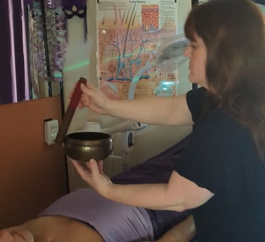 woman using a singing bowl to administer reiki healing energy to client
