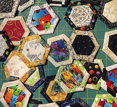 a bunch of quilted fabric hexagons on a cutting board
