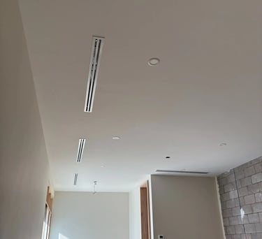 Construcción interior moderna con difusores lineales y iluminación empotrada en techo blanco