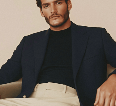 Professional man in navy blue blazer and black turtleneck wearing beige chinos.