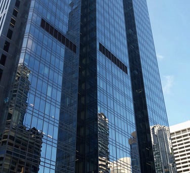 A view of a modern glass skyscraper reflecting a clear blue sky in a major Oceania / Australian city, symbolizing strength and modern legal practice.