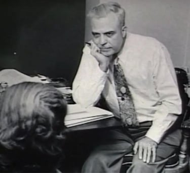 Milton H Erickson sitting at a desk